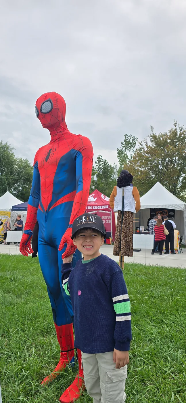 A young patient meets Spider-Man at a Thrive Chiropractic community event in Troy