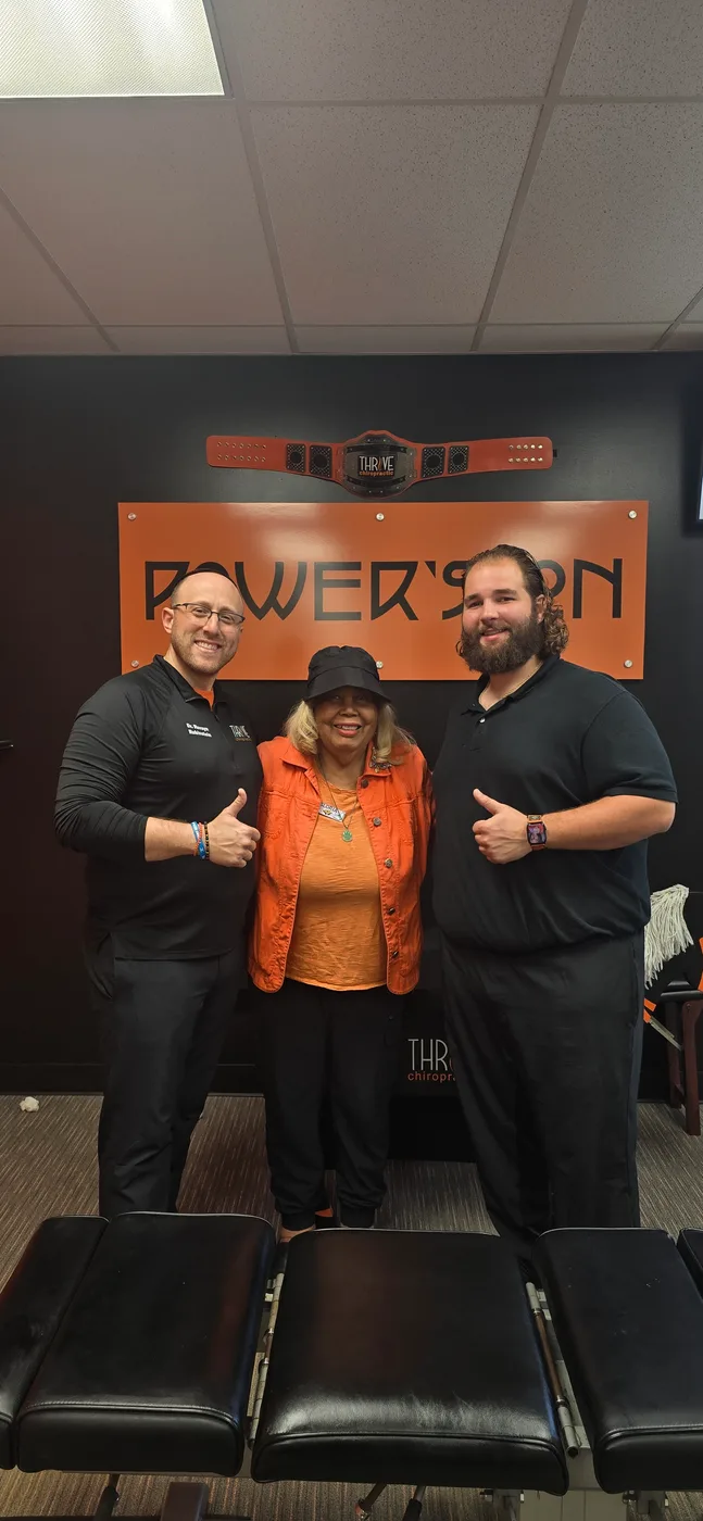 Celebrating at Thrive Chiropractic with the Power's On championship belt