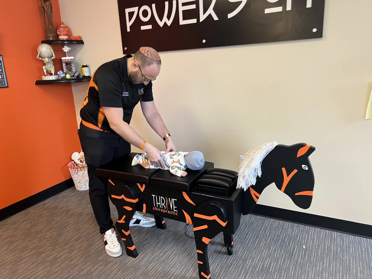 Dr. Rubinstein adjusting a baby on the child-friendly horse-shaped Thrive table.